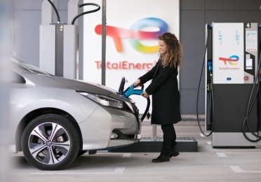 Une femme recharge son véhicule électrique