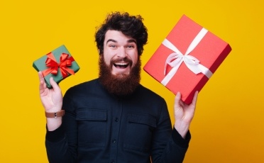 Homme barbu excité et tenant des cadeaux dans les mains