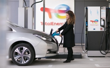 Une femme recharge son véhicule électrique